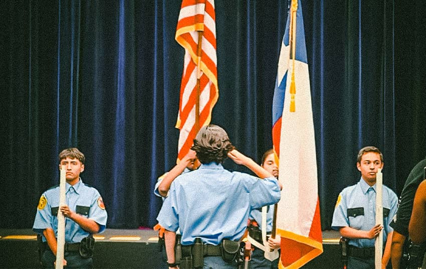 Young cadets saluting American flag.