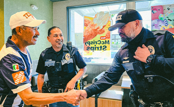 Two officers meeting a male citizen, one officer shaking his hand.